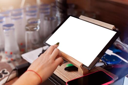 Close up of barista finger with manicure scrolling tablet pc at cafe, plane table with white blank screen, faceless waiter working with online orders, using map case. photo
