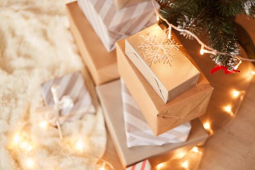 Top view of stack of presents boxes under xmas tree on white soft carpet decorated with garland lights, merry Christmas and happy new year. photo
