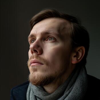 A Man Reflects Quietly, Dressed in a Scarf, Showcasing a Moment of Introspection in Soft Light photo