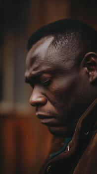 An African-american Man Shows Vulnerability and Sadness While Lost in Thought in a Quiet, Natural Setting photo