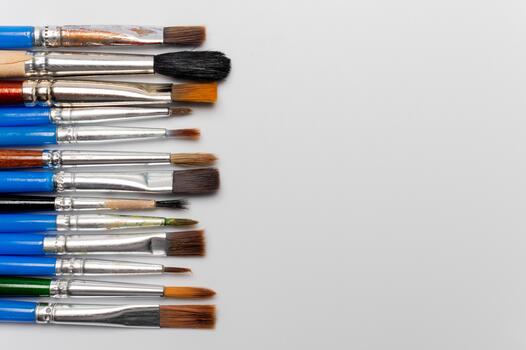 Many different brushes on a white background. Painting tools, a set of dirty paint brushes in a row on a white background, copy space, top view photo