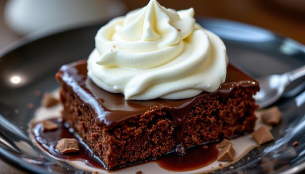 A glossy chocolate dessert topped with smooth whipped cream. photo