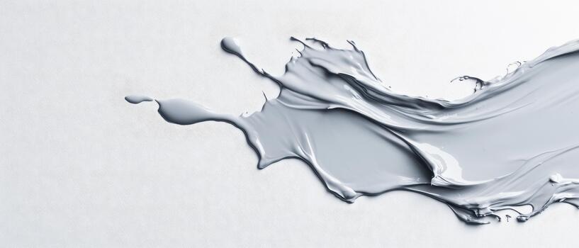 A dynamic splash of grey liquid material spreads across a textured pale surface with fluid motion. photo