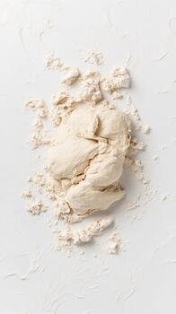 A ball of raw dough rests on a white surface dusted with flour. photo