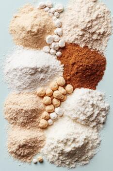 Pile of various dry food powders and small spheres arranged on a soft blue surface. photo
