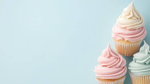 Three pastel frosted cupcakes arranged on a light blue background with empty space for text. photo