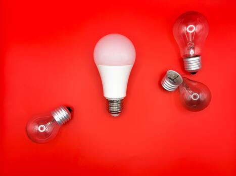 Modern LED lamp, saving electricity. Tungsten light bulb lamp. Non-working light bulb, broken light bulb. Concept of light and dark, idea, electricity copy space, flay lay, red background photo