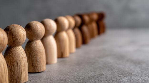 Row of diverse wooden figures illustrating concepts of inclusion unity and human connection on a textured surface with natural light photo