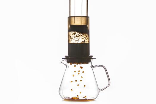 Brewing of Coffee by Creates Pressure Aeropress Method Where Drops Flow From Flask Into Glass Pot, Creating Rich and Fragrant Coffee Drink Against White Background with a Free Copy Space photo