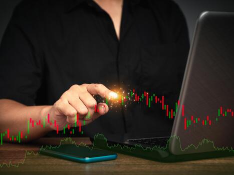 Close-up of a businessman or trader pointing to a graph stock on a virtual screen while sitting at the table. photo