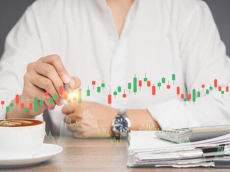 Stock exchange market analysis. Businessman or trader pointing to a graph stock on a virtual screen while sitting at the table. photo