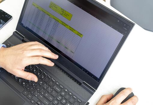 Man sitting at the table, studying n excel sheet on computer screen showing bank loan amortization table. Finance photo