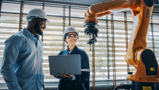 Diverse Engineers Collaborating on Robotic Arm Automation in Modern Factory photo