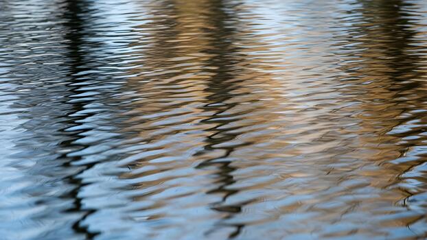 Rippling water reflecting sunlight and trees in abstract patterns photo
