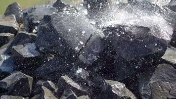 dichtbij omhoog visie van water druppels spatten Aan donker stenen in natuurlijk milieu met dynamisch structuur en contrast video