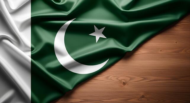 Green and white flag of Pakistan with a crescent and five-pointed star, displayed on a wooden surface. photo