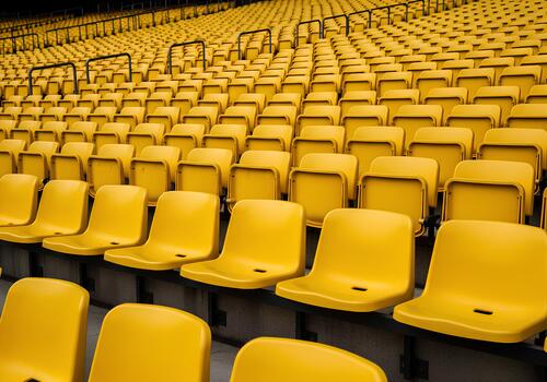 Numerous empty yellow stadium seats arranged in parallel rows, creating a pattern. photo