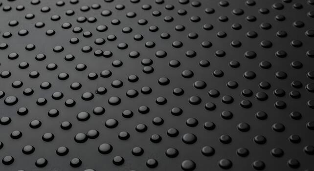 Close-up of a dark textured surface featuring uniform circular bumps arranged in a precise geometric pattern, creating a modern, tactile backdrop with subtle reflections and shadows photo