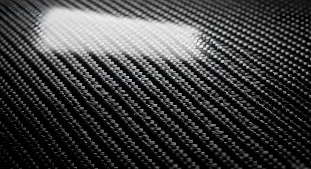 Detailed close-up of black composite material texture with an intricate woven pattern. The glossy, high-tech surface reflects light, emphasizing its modern strength and advanced design photo