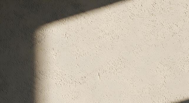 Warm beige textured wall background with a striking diagonal sunlight shadow, creating a dynamic and minimalist backdrop for design projects and abstract architectural concepts photo
