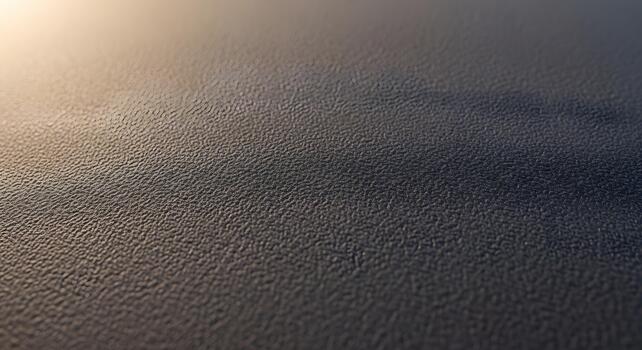 Close-up abstract shot of a dark, rugged surface showcasing intricate textural details and subtle lighting, creating a dramatic and tactile background photo