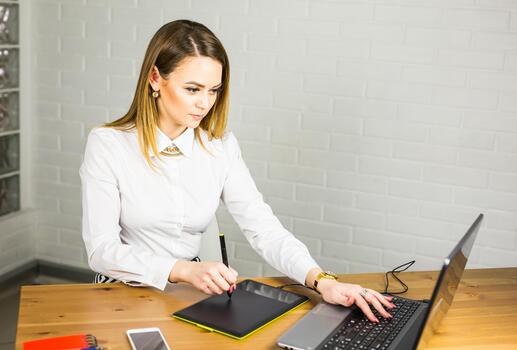 Young Woman designer using graphics tablet while working with computer photo
