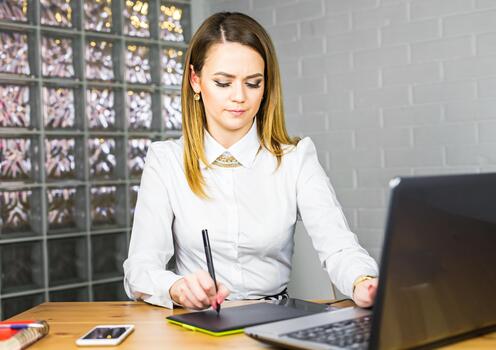 Woman designer using graphics tablet while working with computer photo