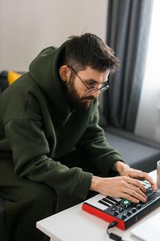 Portrait male music producer or arranger using laptop and midi keyboard and other audio equipment to create music at home studio. Beat making and arranging audio content and composing song photo