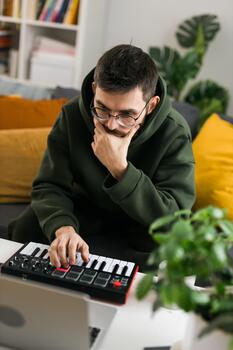 Man music producer or arranger using laptop and midi keyboard and other audio equipment to create music at home studio close-up. Beat making and arranging audio content and composing song concept photo