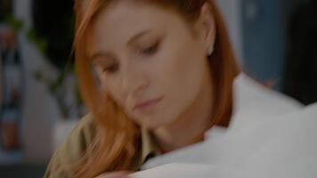 i en Hem kontor miljö, en allvarlig kvinna fokuserar på analyserar Graf ark och dokument. henne händer utforska de papper medan hon förstärker henne förståelse av data. video