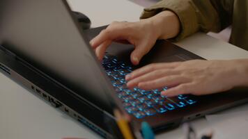 Woman hands swiftly typing on laptop keyboard with illuminated blue keys, demonstrating professional efficiency and focused digital communication in modern workplace setting video
