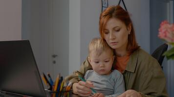 multitasking Lavorando madre analizzando attività commerciale grafici mentre Tenere infantile a casa ufficio durante a distanza opera sessione video