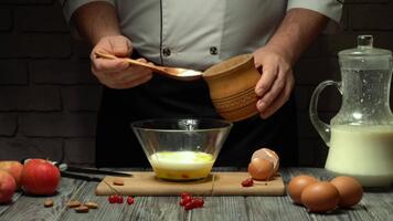 nel un' rustico cucina, un' capocuoco è miscelazione uova e latte nel un' chiaro ciotola. circostante lui siamo fresco mele, uova, e un' brocca di latte. il atmosfera è caldo e invitante. video