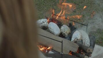 fuoco fossa con al forno Patata e fiamme, accogliente fuoco di bivacco e irriconoscibile persona video
