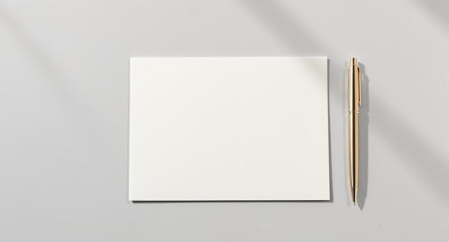 Elegant gold pen rests beside blank white card ready for your message or invitation, set against a soothing gray background for creative projects photo