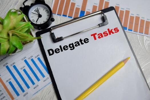 Concept of delegate tasks write on clipboard with financial graphs isolated on Wooden Table. photo
