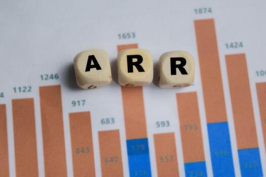 ARR - Annual Recurring Revenue stacked wooden cubes with financial graphs on the table. photo
