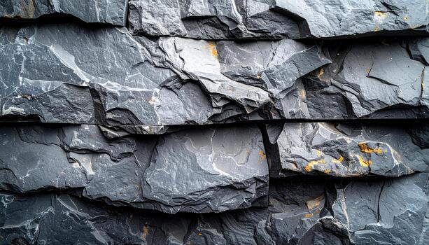 Close up shows the textured surface of a stacked dark gray stone wall creating a rugged and interesting architectural background element. photo