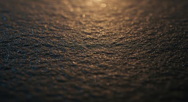 Close up macro shot shows the dark textured surface of a slate stone with glitte reflections in the dim light creating an interesting effect. photo