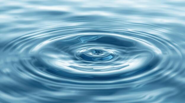 A single drop of water creates concentric ripples expanding outwards on a calm serene blue surface showing fluid dynamics and liquid motion. photo
