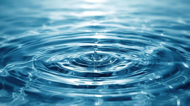 A single water droplet creates concentric ripple patterns across the clear blue liquid surface evoking tranquility and purity of nature. photo