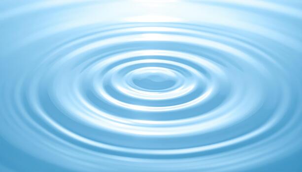 Circular ripples expand outward across the calm surface of the clear blue water creating an ethereal and mesmerizing visual effect. photo
