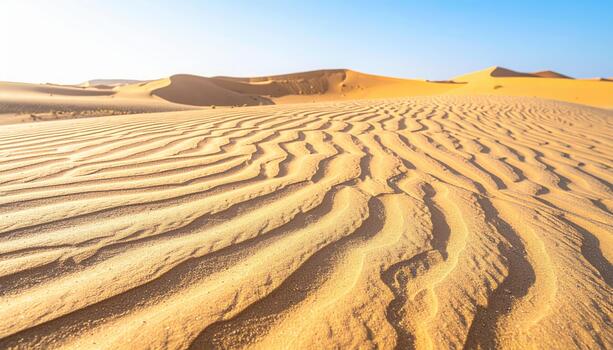 Wavy patterns formed by winds create striking textures in the vast expanse of the Sahara desert under a clear, bright, blue sky. photo