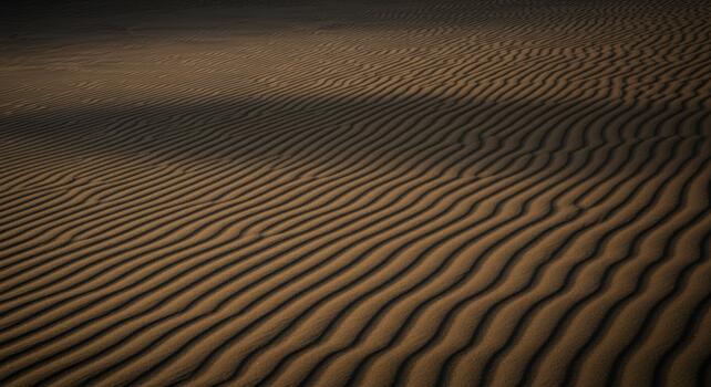 Sunlit sand dune patterns create dramatic shadows across a vast desert landscape showcasing nature's beauty and serene environment. photo