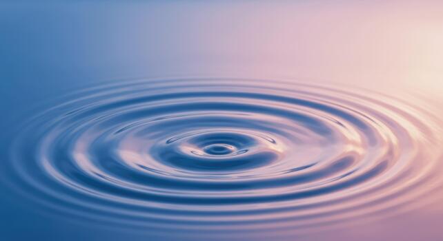 Water droplet impact creates concentric circular ripples spreading across a calming blue and pink gradient surface in soft morning light. photo