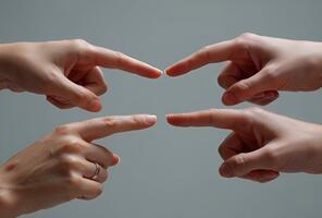 Four hands pointing fingers towards each other in a studio setting symbolizing connection collaboration and direction with a neutral background video