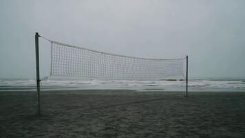tömma strand volleyboll netto på en molnig dag med kraschar vågor. video