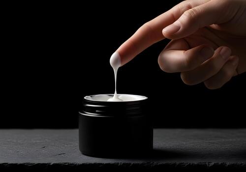 Elegant close up of cosmetic cream jar with a finger testing the texture and consistency on a sleek dark background representing skincare wellness and personal care routine photo