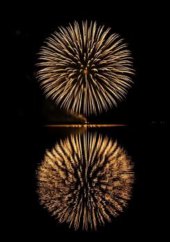 Golden Fireworks Burst Reflected in Dark Water Celebration and Night Sky Display Magnificent Pyrotechnics Exploding in Brilliant Light with Mirrored Image photo