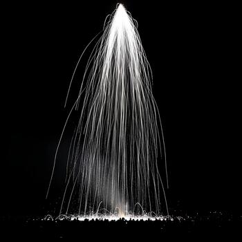 Spectacular display of white fireworks exploding against a dark night sky illuminating the ground in a mesmerizing visual show of light and color photo